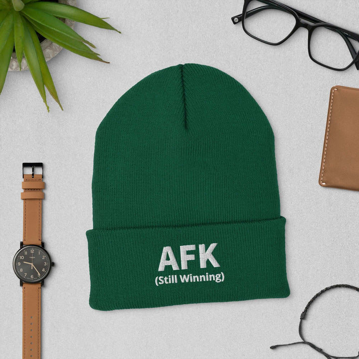 AFK Cuffed Beanie in green, featuring 'AFK (Still Winning)' text, styled with accessories.